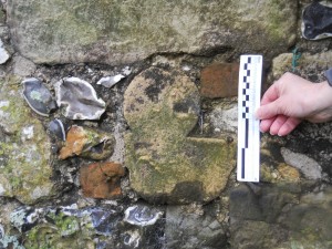 Reused embedded shaft  stone in NE facing wall of shed